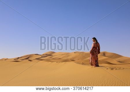 Girl In Moroccan Dress In Sahara Desert.