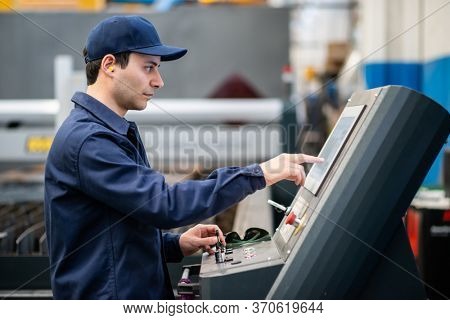 Factory worker using a plasma cutting machine