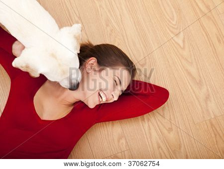床と彼女の顔をなめる彼女の犬に横たわっている女性