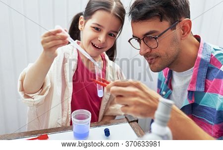 Little Girl And Her Father Doing Science Experiments In The Laboratory. Dad And Daughter Study Chemi
