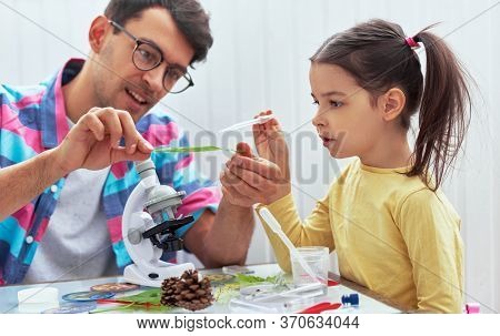 Handsome Dad And Cute Daughter Study Biology And Chemistry Lesson With Microscope. Little Girl With 