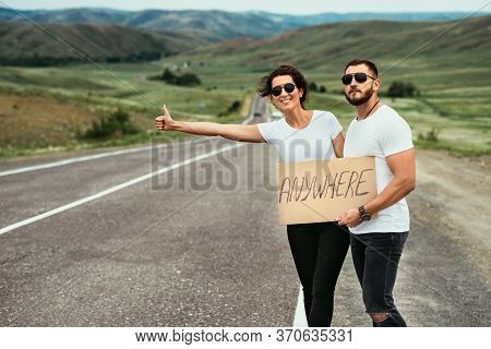 A Man And A Woman Are Hitchhiking. A Young Couple Goes Hitchhiking Around The Country. Free Hitchhik