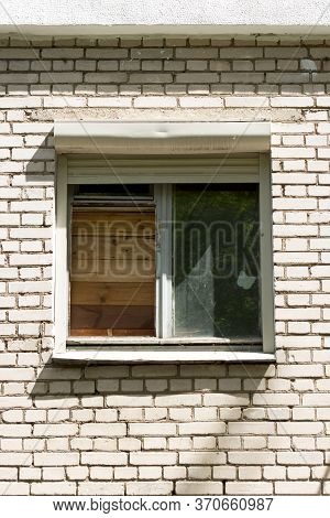An Old Broken Clogged Window In A White Brick Apartment Building.