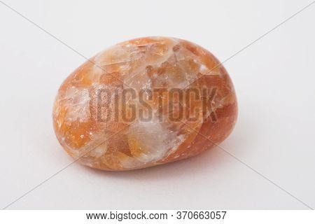 An Orange Calcite Gemstone Against A White Background