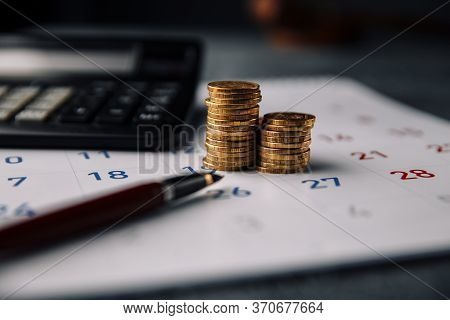 Calendar, Calculator And Stack Of Coins In A Office