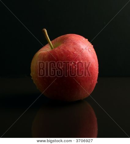 Manzana roja en la superficie reflectante negra