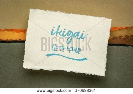 ikigai - Japanese philosophy and life style  - a reason for being or a reason to wake up  - handwriting on a handmade rag paper against abstract landscape