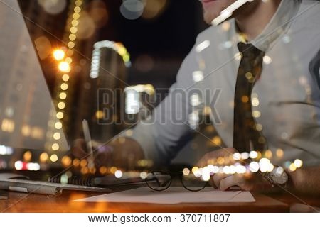 Double Exposure Of Night Cityscape And Young Man Working In Office, Closeup. Financial Analytics