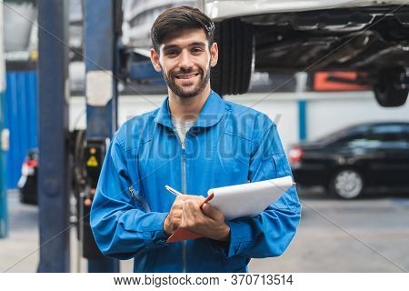 Auto Check Up And Car Service Shop Concept. Mechanic Writing Job Checklist To Clipboard To Estimate 