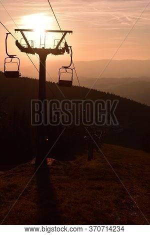 Ski Chair Lift In The Mountains At Pink Sunrise. Vertical Photo.