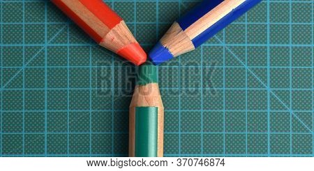 Rgb (red, Green, Blue) Colored Pencils Converging Towards The Center Of A Dark Green Cutting Mat