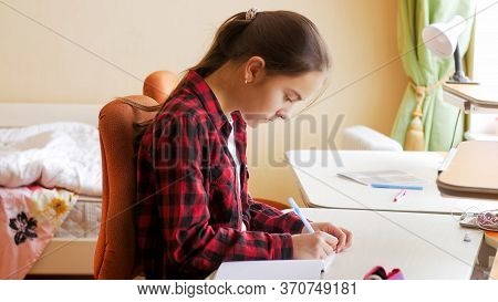Portrait Of Teenge Girl Studying And Doing Homework In Her Bedroom