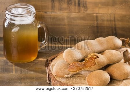 Tamarind Juice In A Glass Surrounded By Fresh Ripe Tamarinds - Tamarindus Indica