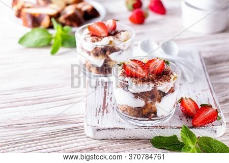 Layered Trifle Dessert With Sponge Cake, Whipped Cream And Strawberries In Serving Glasses On A Whit