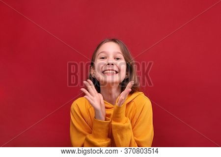 A Happy Girl In An Orange Retinue Breaks In The Palm Of Her Hand And Smiles.
