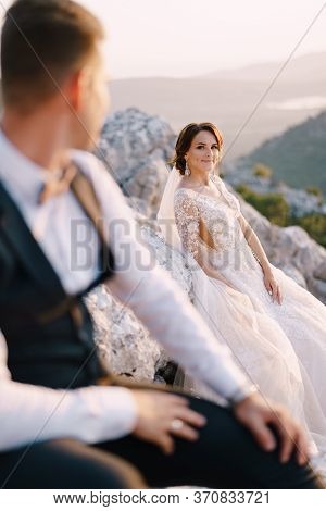A Wedding Couple On Top Of A Mountain In The Bay Of Kotor, The Bride Smiles To The Groom At Sunset. 