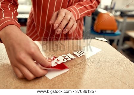 Cropped Shot Of Woman Removing The Backing From Advertisement Sticker With Text While Preparing It T