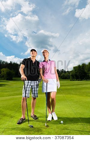 Młoda para sprawny, gry w golfa na polu golfowym, oni z pewnością ćwiczenia lub szkolenie