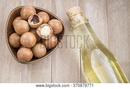 Nuts And Macadamia Oil On Wooden Background - Macadamia Integrifolia