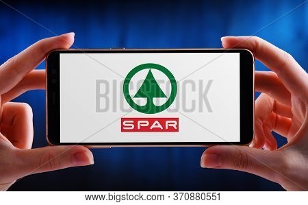 Hands Holding Smartphone Displaying Logo Of Spar