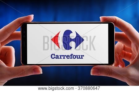 Poznan, Pol - May 21, 2020: Hands Holding Smartphone Displaying Logo Of Carrefour S.a., A French Mul