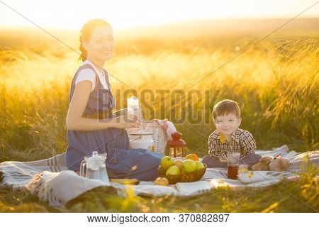 Pregnant Mother And Her Cute Little Son Outdoors. Happy Family And Healthy Eating Concept