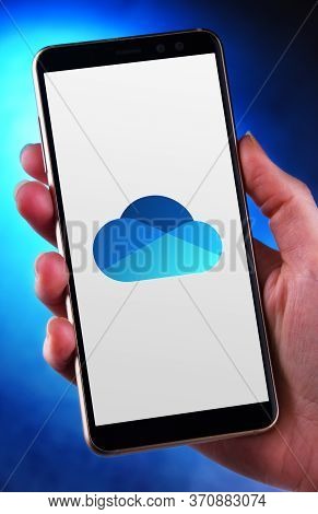 Poznan, Pol - May 21, 2020: Hand Holding Smartphone Displaying Logo Of Microsoft Onedrive, A File Ho