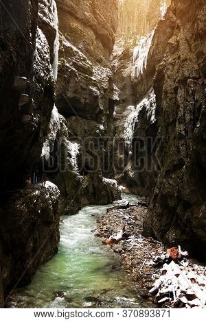 Tourists In Snow-covered Icicles At Partnachklamm, Famous Tourist Destination. Partnachklamm In Garm