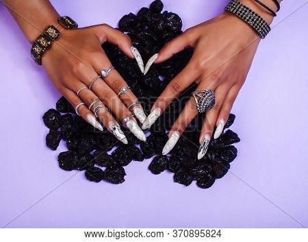 Woman Hands With Long Nails Manicure Holding Dry Fruits In Shape Of Heart On Purple Background