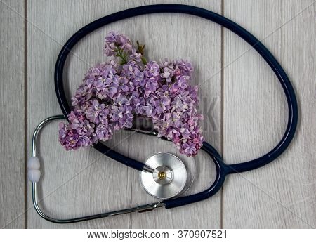 Lilac Branch And Stethoscope On Beautiful Wooden Table. Concept. Beautiful Background, Copy Space.