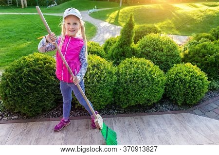 Cute Adorable Little Caucasian Girl Hepling Parents Sweeping Yard With Broom On Warm Bright Autumn E