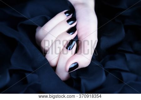 Female Hand With Black Manicure On A Black Background