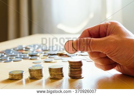 Selective Focus Asian Men Hand Put Coin Into Stack With Piggy Bank On Background. Saving Plan For Re