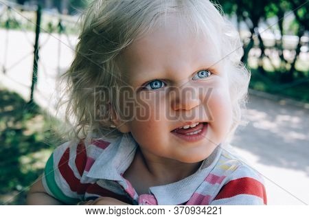 Portrait Of A Cute Happy Little Boy With Blond Hair And Blue Eyes, Whearing A Hat, Smiling And Playi