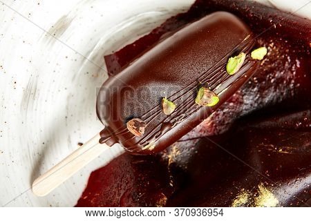 Chocolate mousse dessert close up. Luxury restaurant sweet course side view. Ice cream served with pastila in deep craft plate. Fancy confectionery dish with jellied fruit sweetmeat. Sweet food