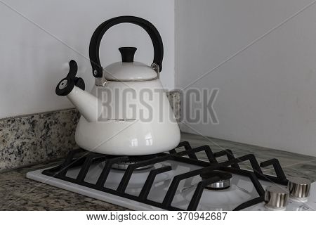 Close Up: A White Stylish Kettle With A Wistle On A Small Gas Stove In A Kitchen