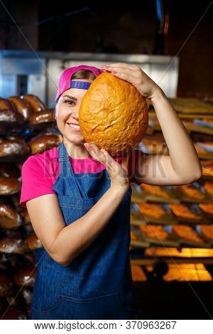 The Stage Of Baking In A Bakery. Portrait Of A Baker Girl With Bread In Her Hands Against The Backgr