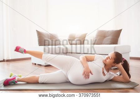 A Pregnant Woman Works Out On A Yoga Mat At Home. Pregnancy And Sports. Oga And Pilates For Pregnant