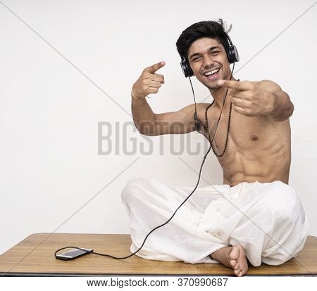 Young Indian Handsome Boy Wearing Dhoti,listening To Songs On His Headphones, Cheerful And Happy.
