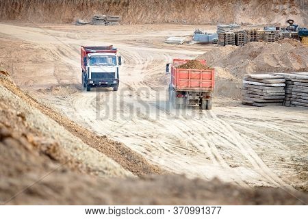 Two Multi-ton Heavy Mining Dump Trucks Empty And Loaded During Removal Of Construction Soil From Con