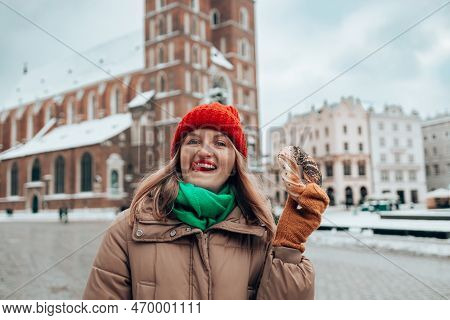 Xmas Tourist Woman In A Bright Hat And Warm Jacket Holding Baked Obwarzanek Traditional Polish Cuisi