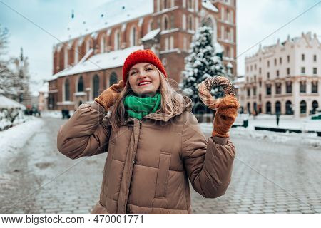 Xmas Tourist Woman In A Bright Hat And Warm Jacket Holding Baked Obwarzanek Traditional Polish Cuisi