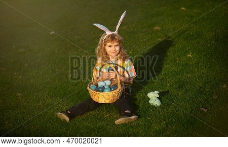 Child With Easter Eggs In Basket Outdoor. Boy On Grass In Park. Easter Egg Hunt. Fynny Kids Portrait