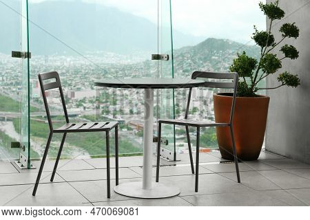 Coffee Table And Chairs Against Picturesque Landscape Of City In Cafe