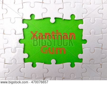White Puzzle With The Word Xanthan Gum On A Green Background.