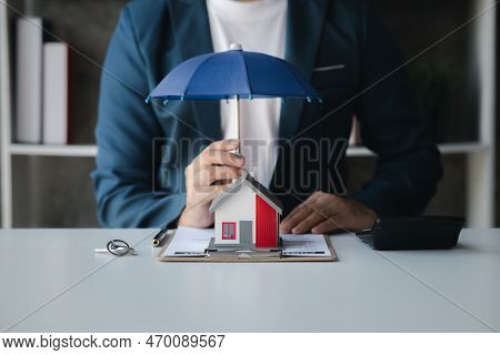 Individuals Holding Small Umbrellas And Model Homes, Housing Insurance Against Impending Loss And Fi