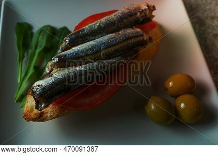 Tapa Of Sardines On A Slice Of Bread With Tomato And Olives On A White Plate With A Typical Spanish 