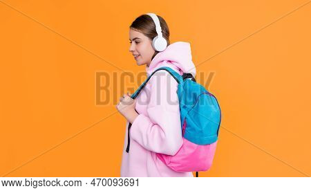 Happy High School Student Girl In Headphones With Backpack On Yellow Background