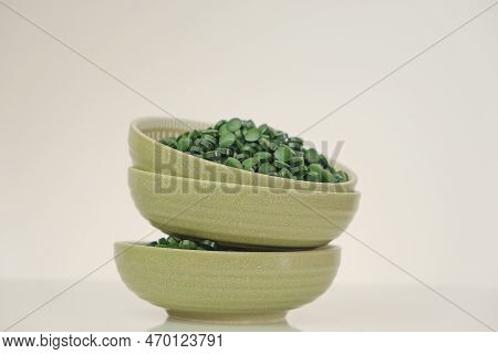 Spirulina Pills In Green Cups .green Spirulina Tablets On Green Background.spirulina Algae Tablets. 