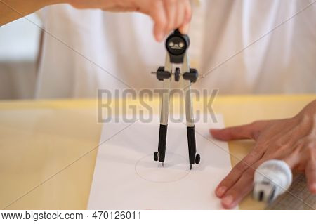Female Hand Using A Measure Circle Preparing To Draw And Sketch On The Empty White Paper.